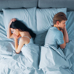 Anorexic couple laying apart in bed
