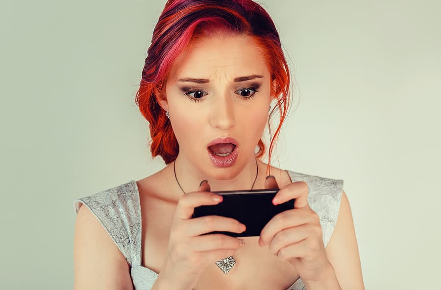 Betrayal Triggers: A picture of a woman negatively reacting to discovering something about her sexually addicted husband on her phone.