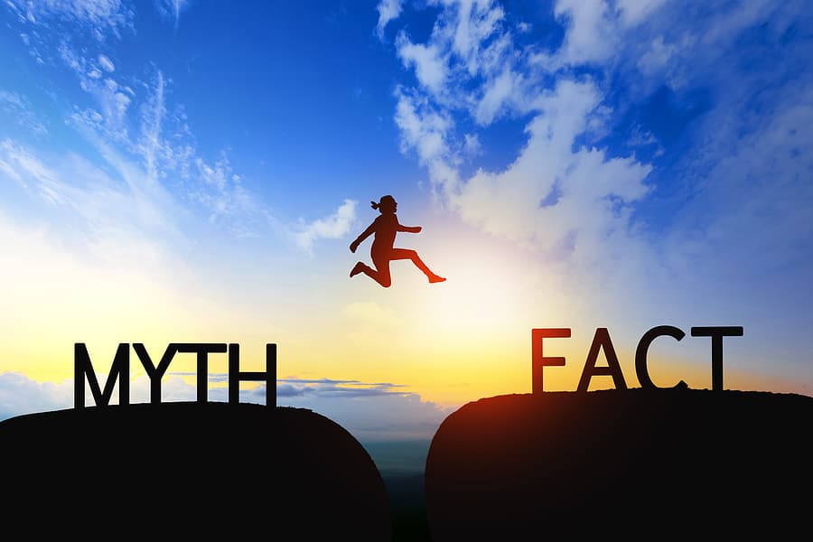 A person is leaping over a gap between 2 cliffs, one labeled a myth and the other fact representing making a resolution.